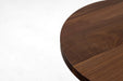 Curved edge of a dark-brown walnut table top showing layered wood grain.