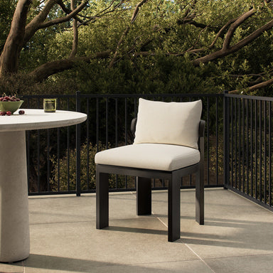 Light gray linen outdoor dining chair with seat cushion and back pillow on black frame