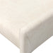 Close-up of off-white upholstered chair front corner with rounded arm and seam.