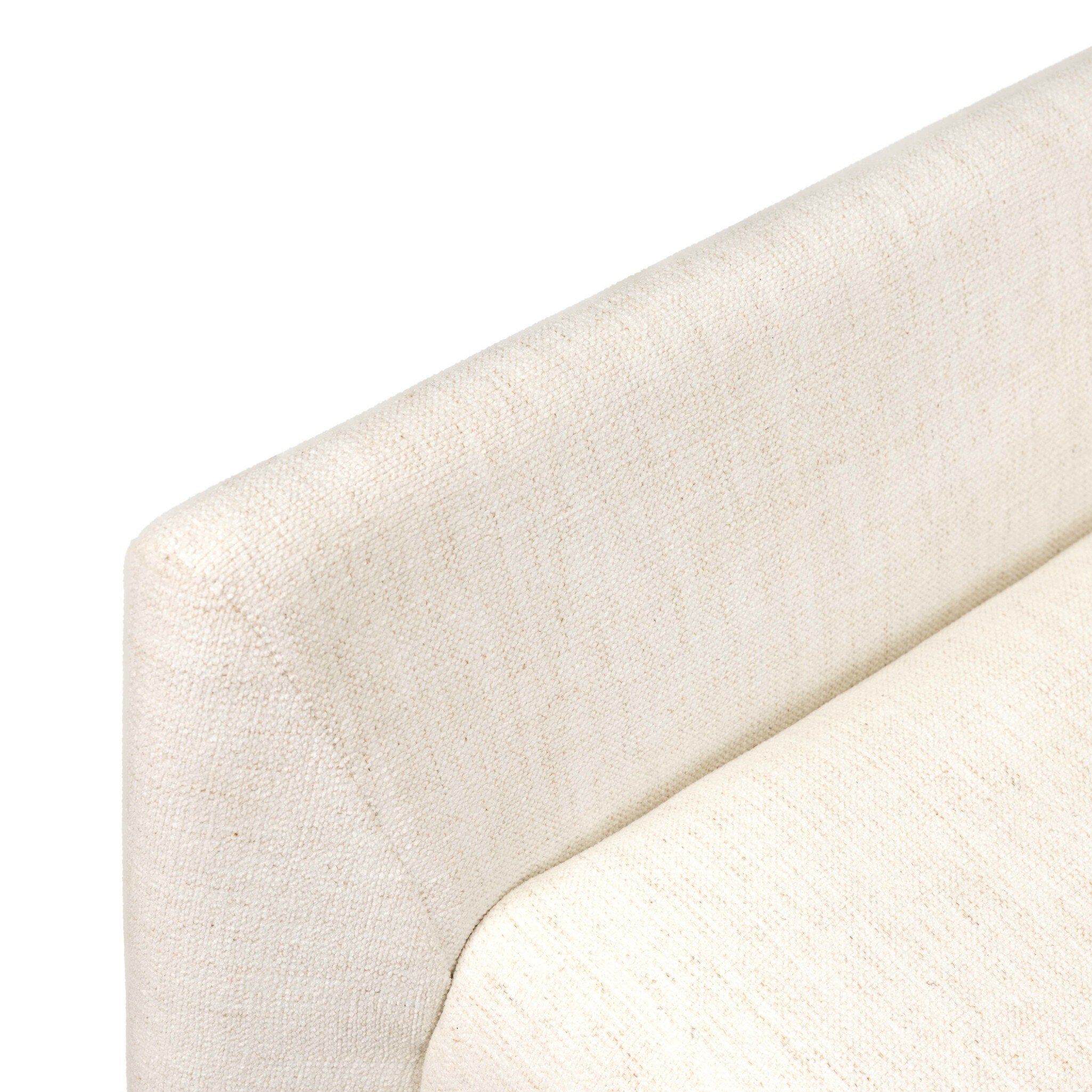 Close-up of off-white upholstered chair armrest with textured fabric surface.