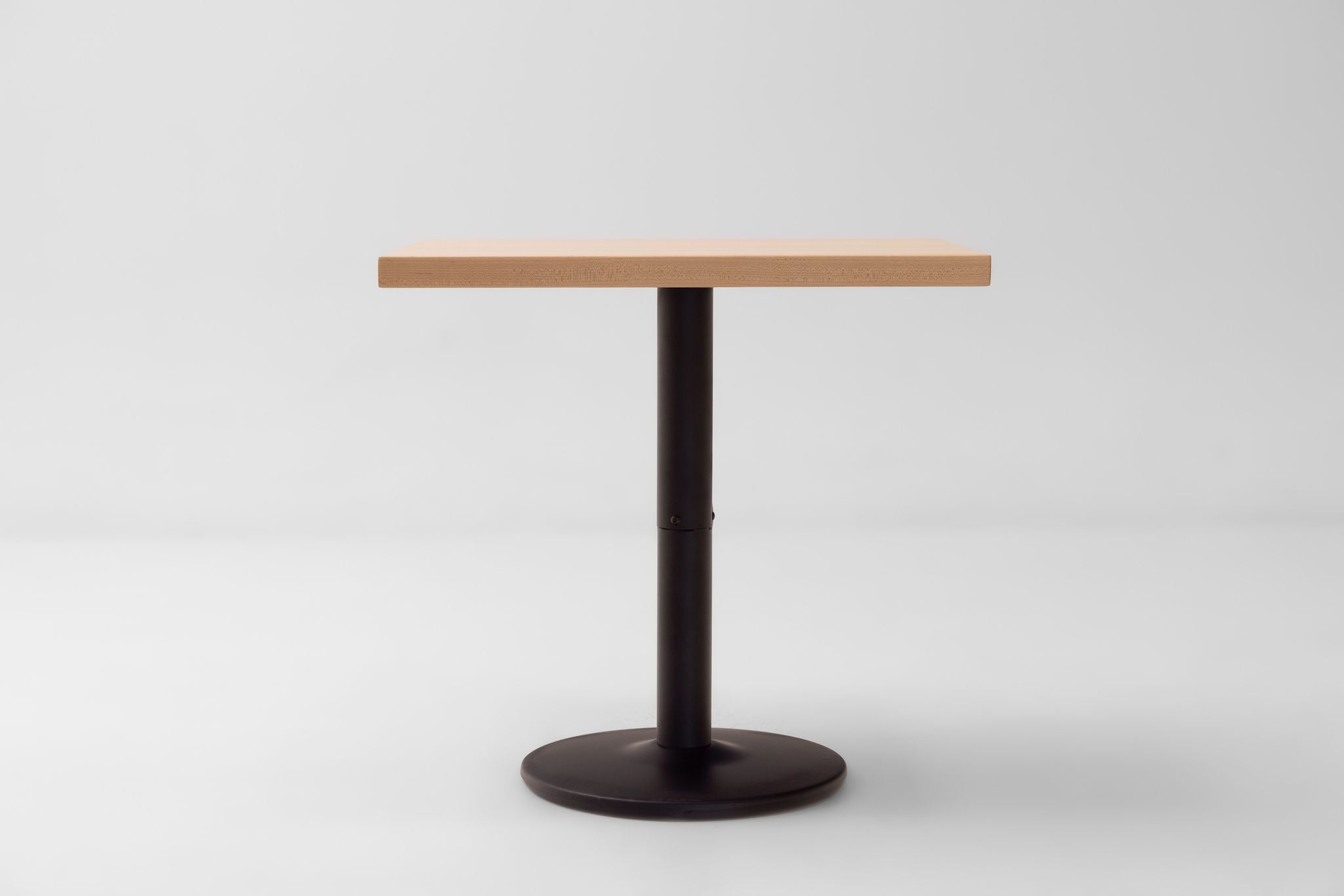 Rectangular maple table top with straight edges on a black round pedestal base