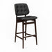 Tufted bar stool with black tufted seat, dark wood frame, and lower footrest
