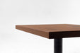 Walnut tabletop edge detail with warm brown grain and squared corner