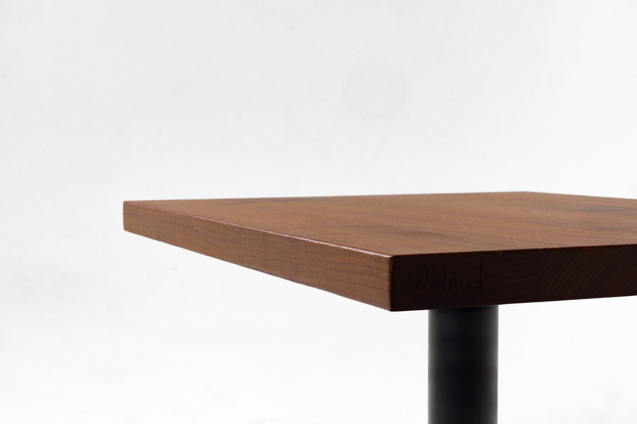 Walnut tabletop edge detail with warm brown grain and squared corner