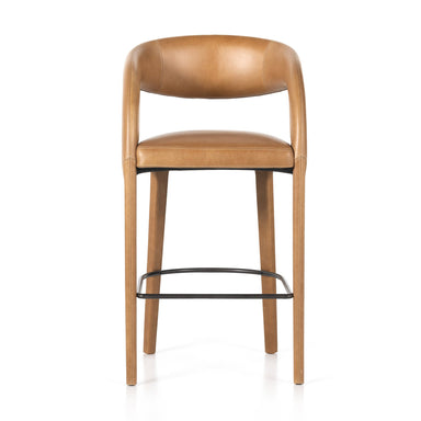 A butterscotch brown leather bar counter stool with a curved backrest and a metal footrest.
