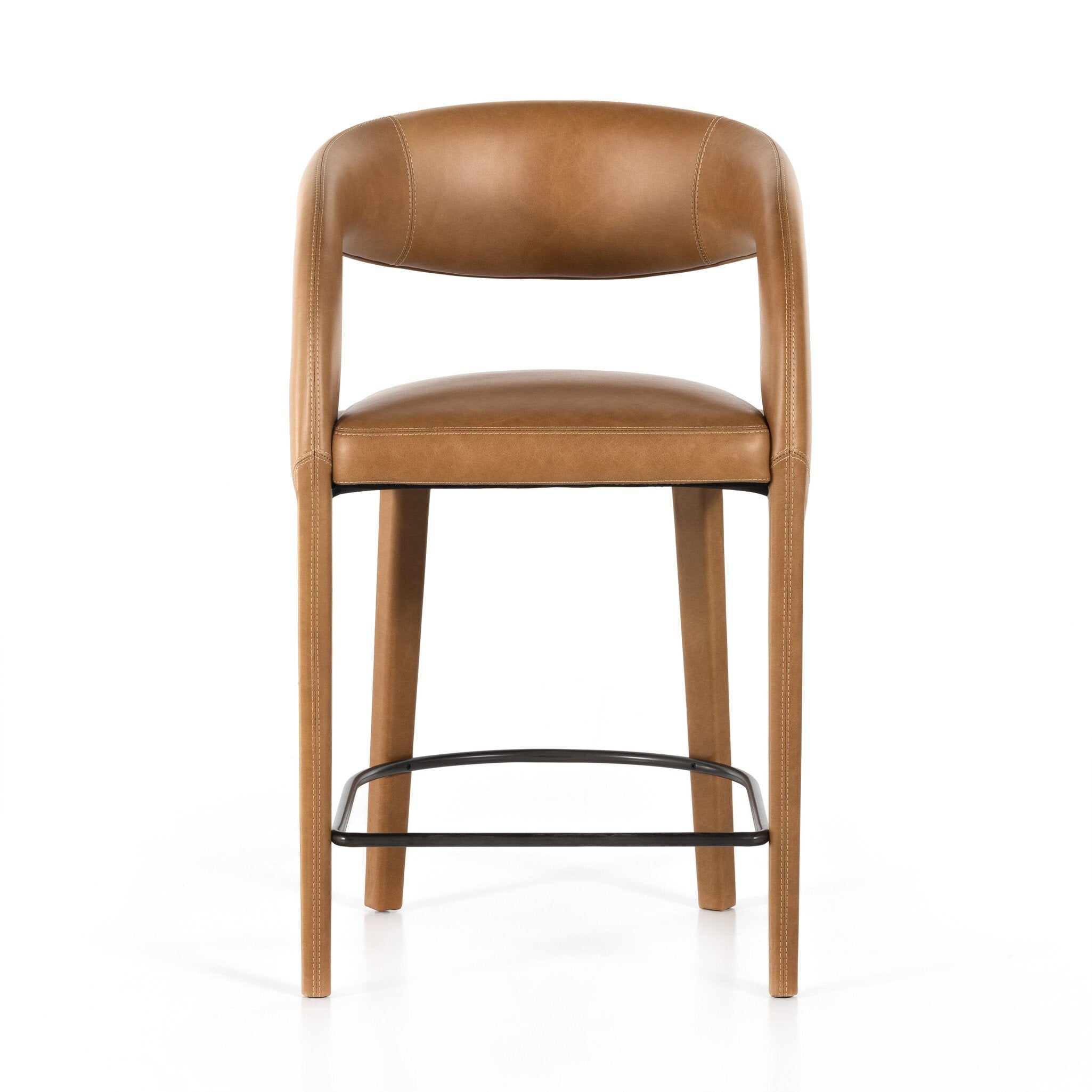 Counter stool with tan upholstered seat and back, curved arms, wood legs, black footrest.