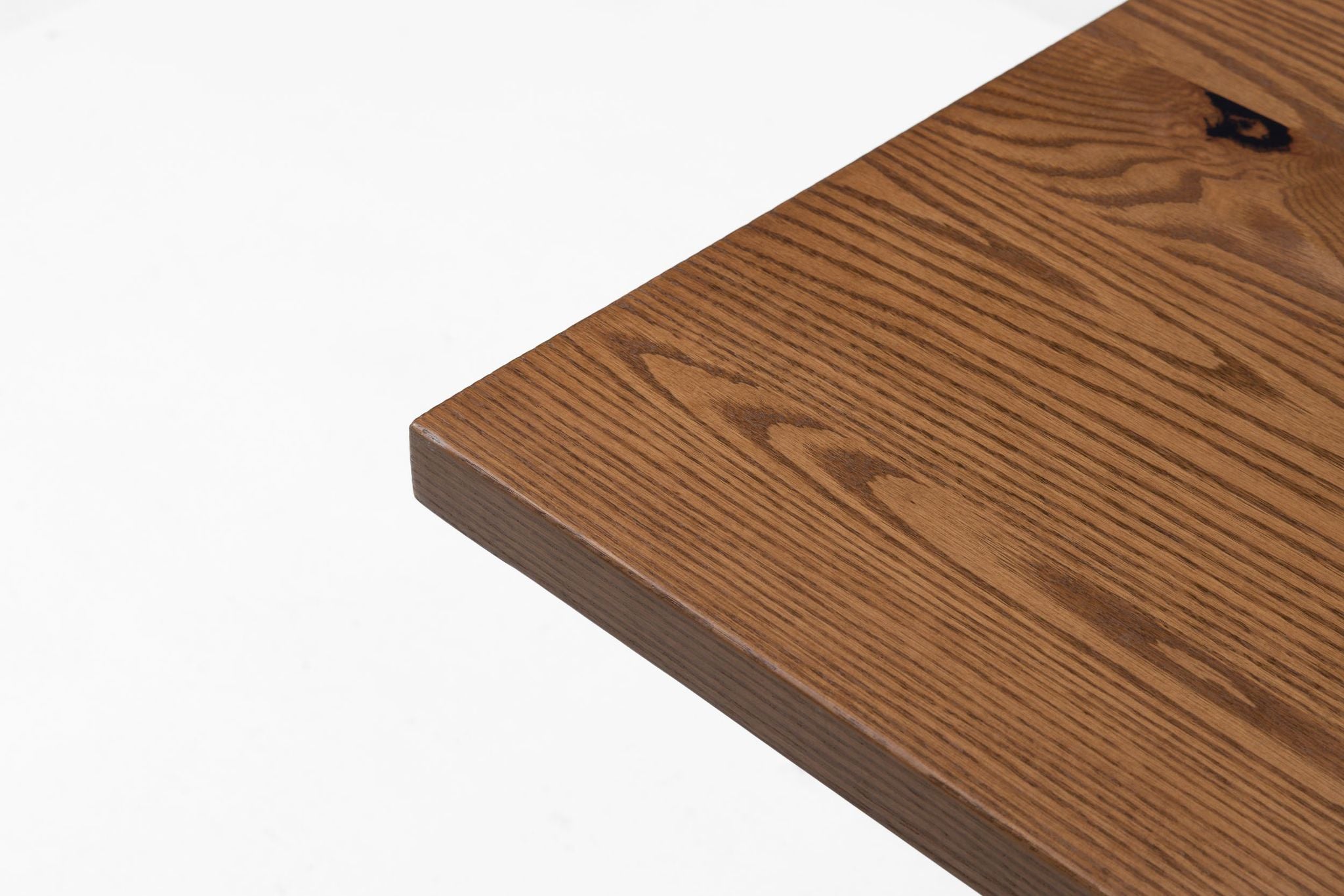 Red oak tabletop corner with textured wood grain and beveled edge
