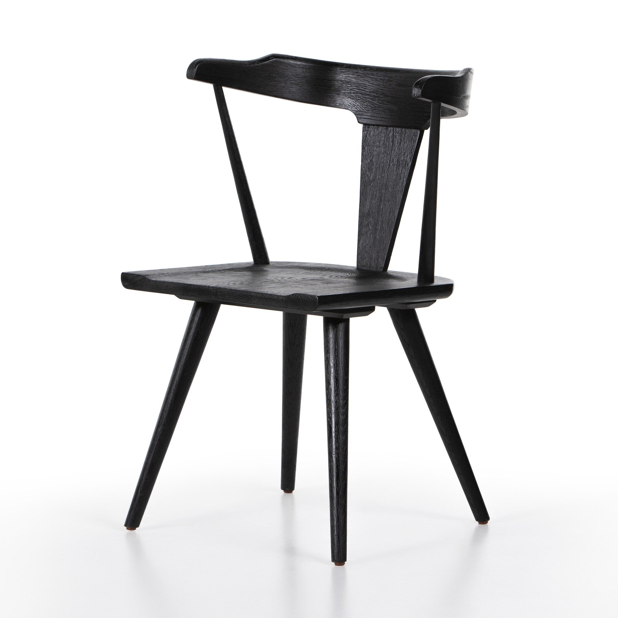 Black wooden chair on a white background. Angled Ripley Dining Chair in Black Oak with mid-century Windsor-style sculptural silhouette.
