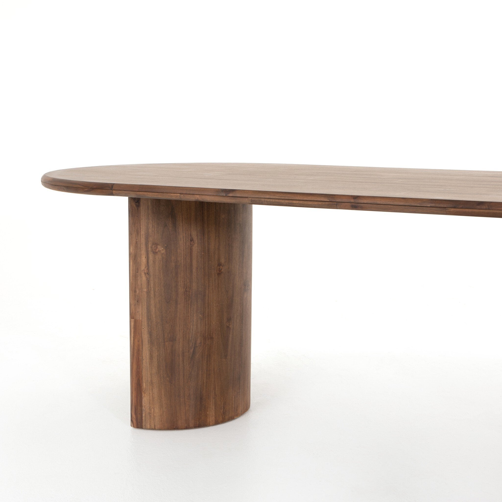 Angled leg view Paden Dining Table in Seasoned Brown Acacia with crescent-shaped legs and an oval tabletop