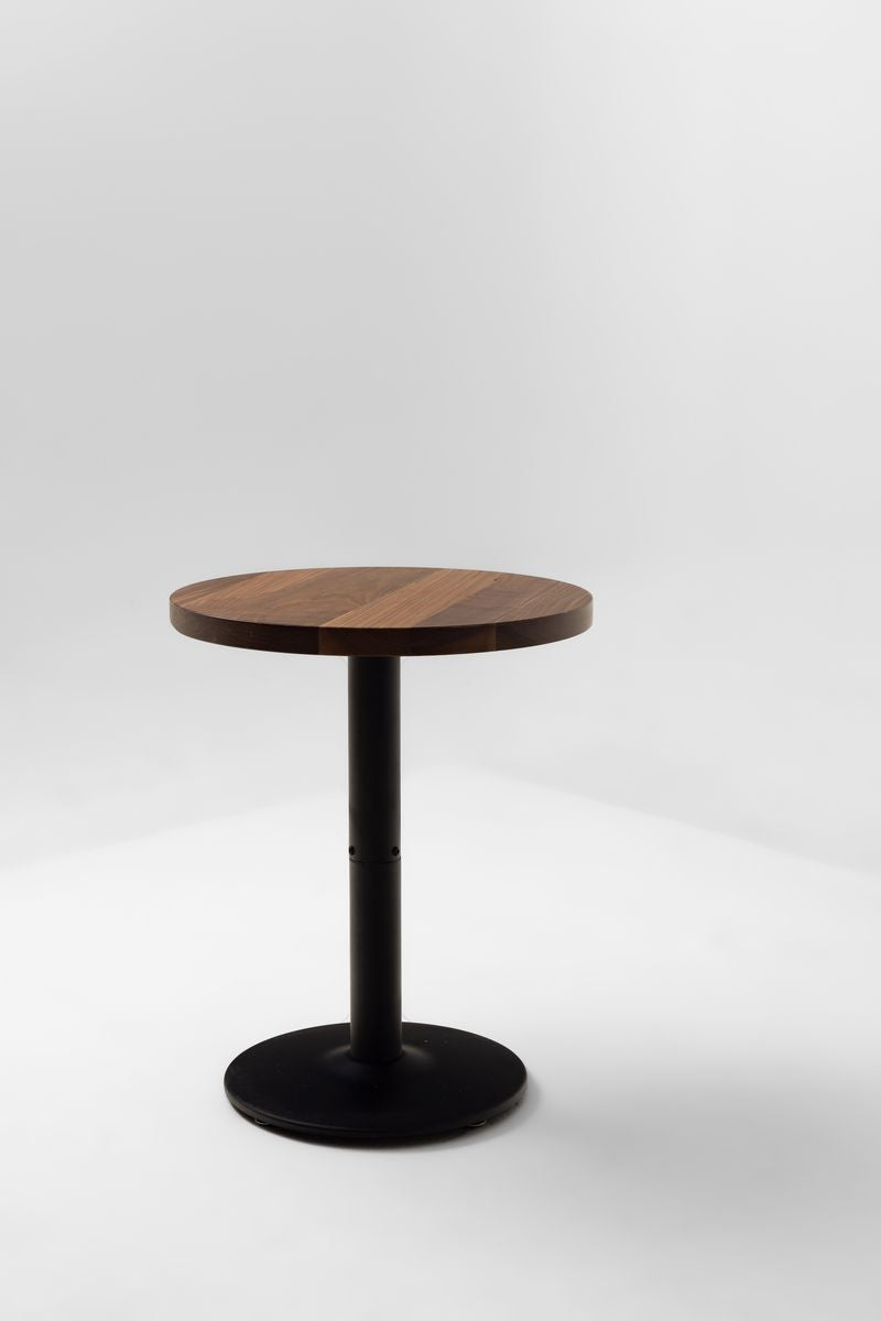Walnut round table top with dark finish on a slender dark pedestal base.