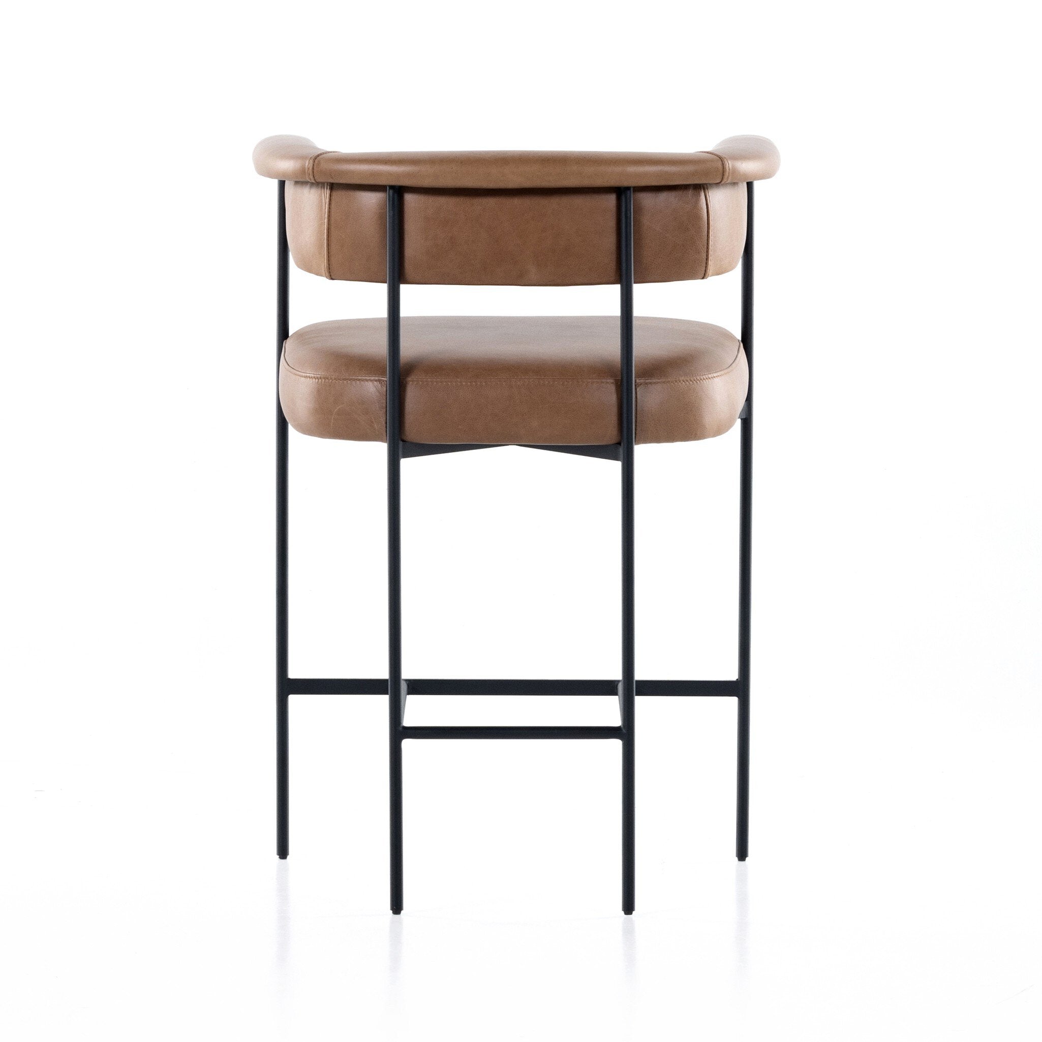 Tan cushioned counter stool with padded backrest, round armrests, and black metal frame