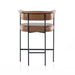 Tan cushioned counter stool with padded backrest, round armrests, and black metal frame