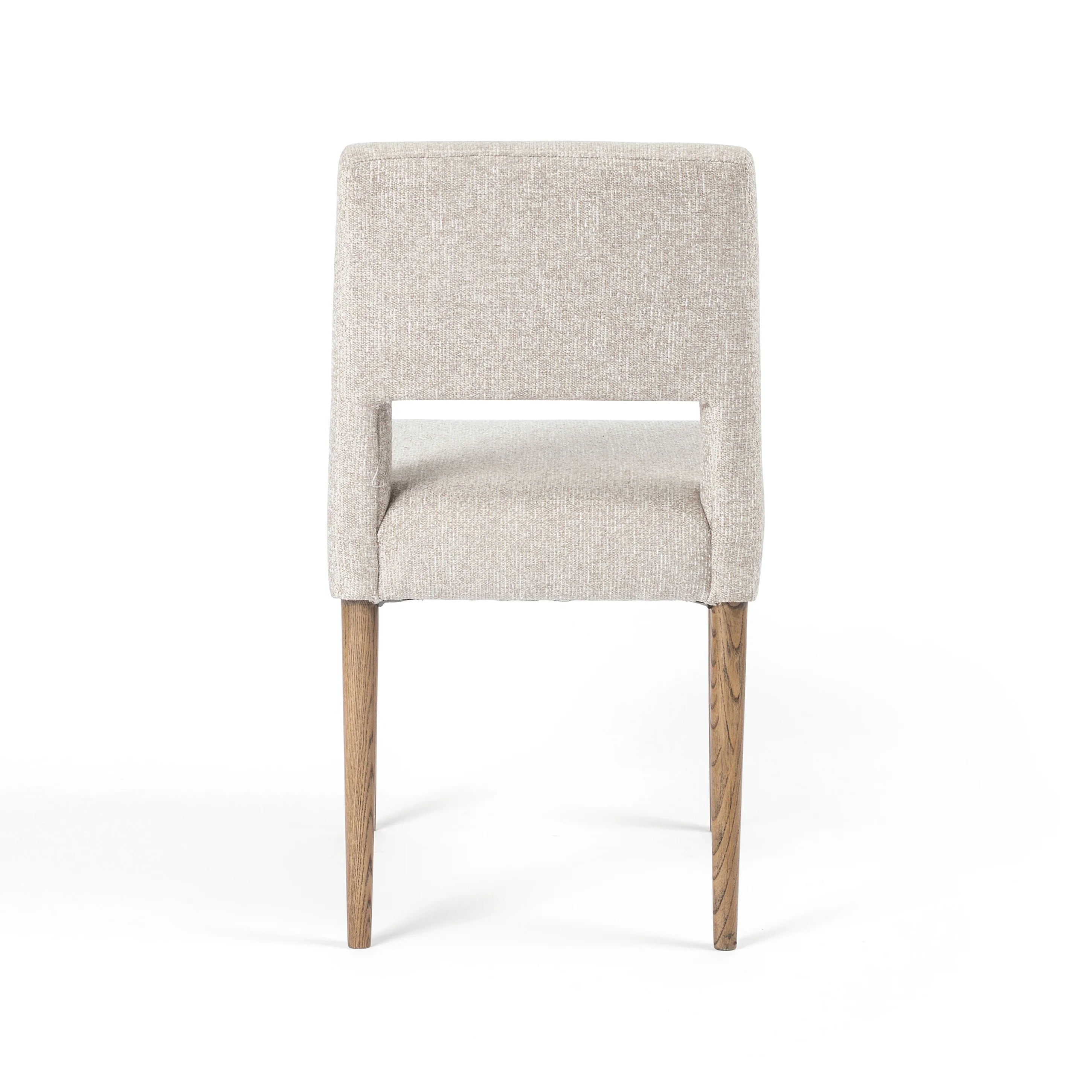 Armless dining chair front view with light camel upholstered back and seat, wooden legs.