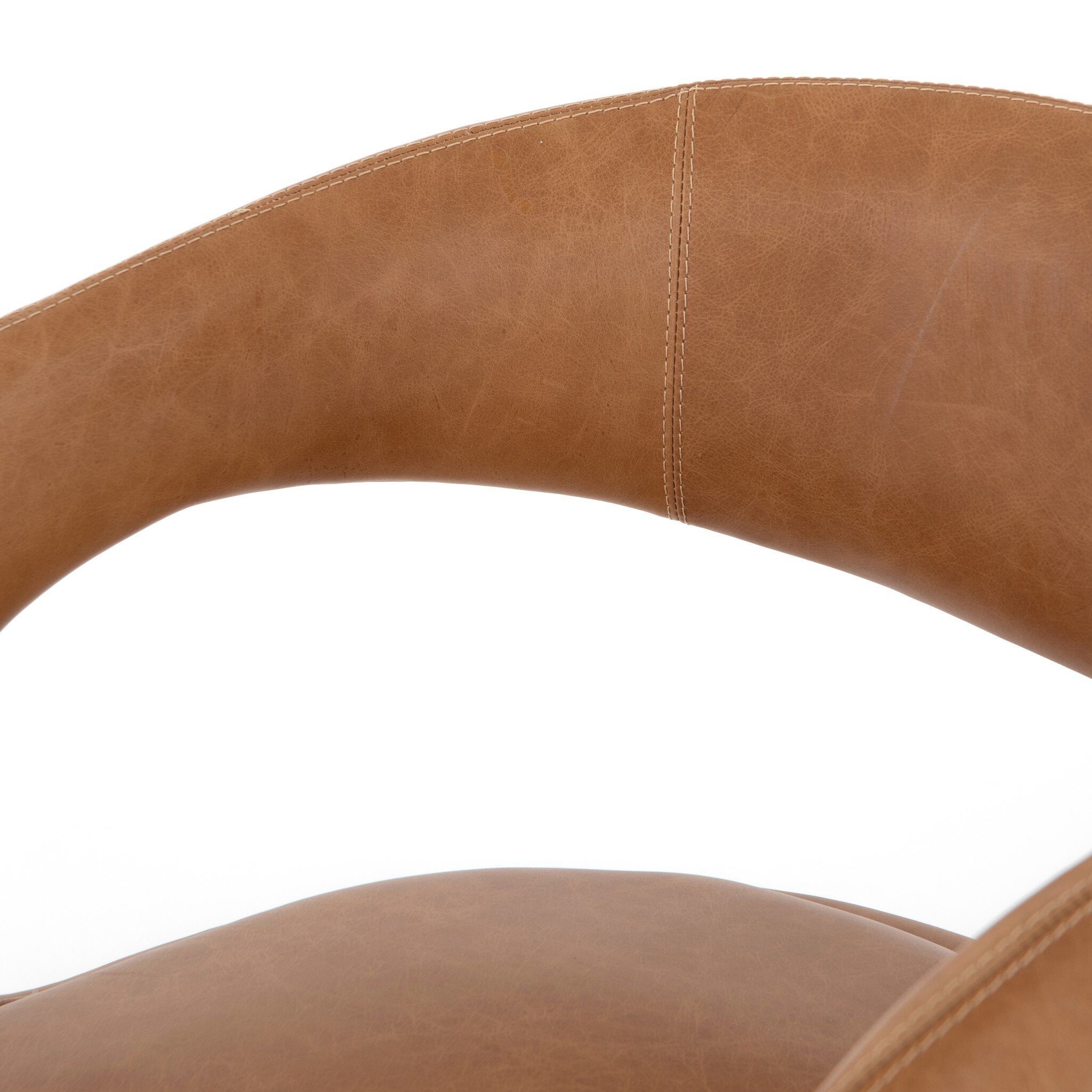 Close-up of a brown leather chair with visible stitching on a white background. Back rest Hawkins Dining Chair in Sonoma Butterscotch top-grain leather with a sculpted open-back frame.