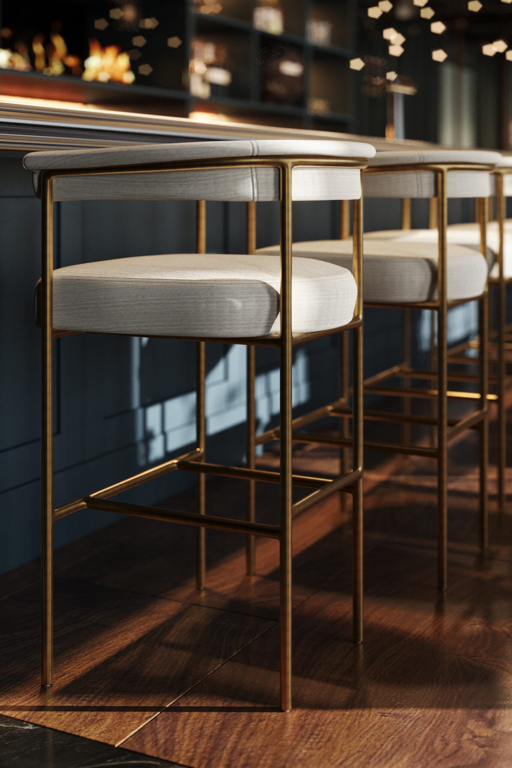 Upholstered bar stool with light fabric seat and rounded back, gold metal frame.