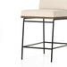 Counter stool with light cream upholstered seat and back, black metal base and footrest