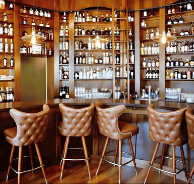 Brown Button tufted cowboy stool showcasing a rugged refined silhouette and precision swivel mechanism for hospitality use