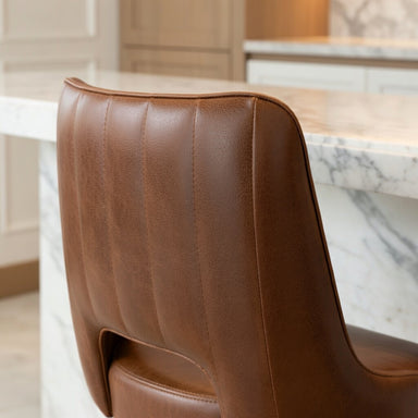 Brown Modern Rowan bar stool featuring a softly cushioned seat and a grounded metal frame with clean architectural lines for hospitality use