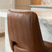 Brown Modern Rowan bar stool featuring a softly cushioned seat and a grounded metal frame with clean architectural lines for hospitality use