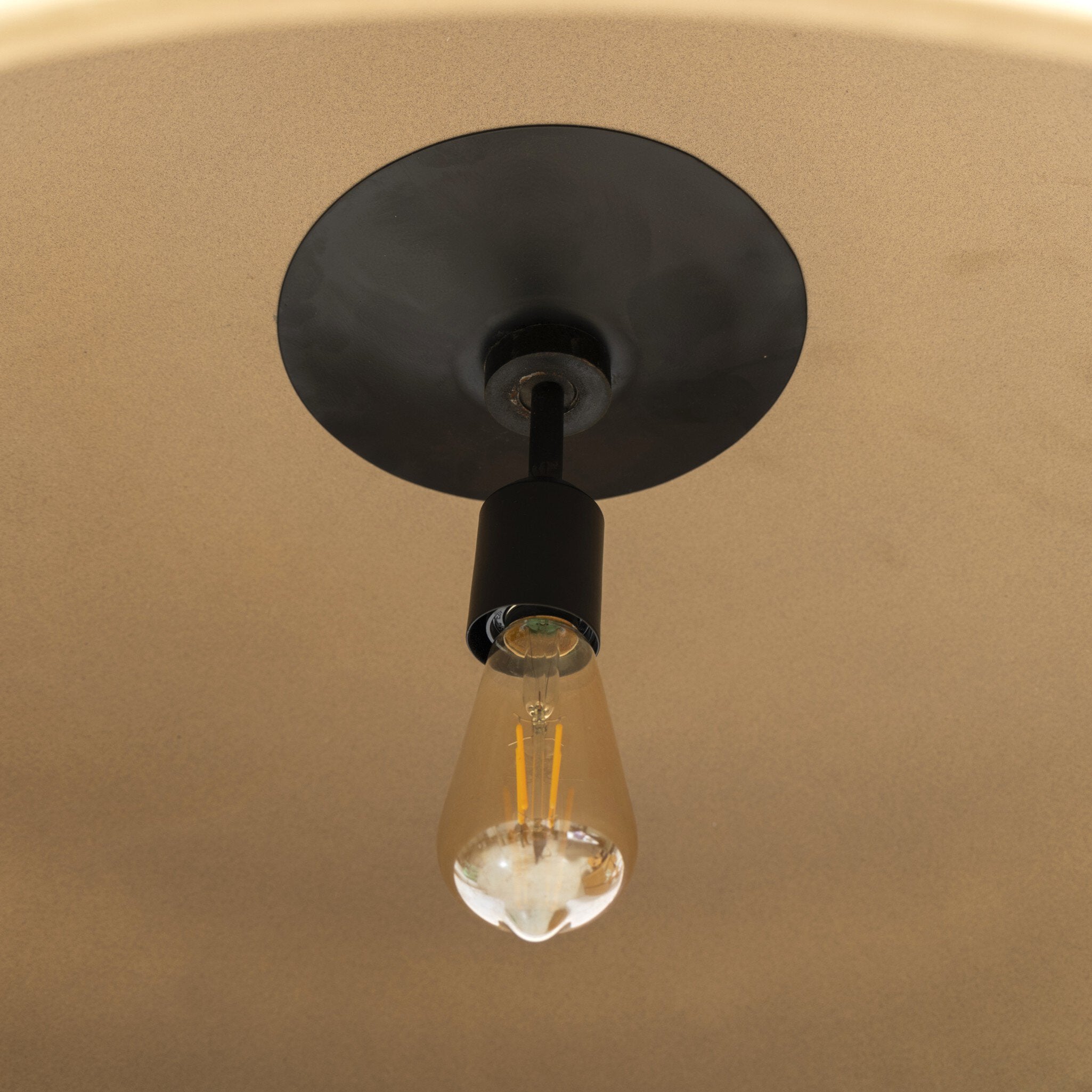 Lit bulb detail of Jesenia 27.5-inch diameter tan speckled ceramic pendant light with oversized black iron chain links