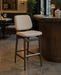 Upholstered bar stool with beige seat, dark wood legs and footrest