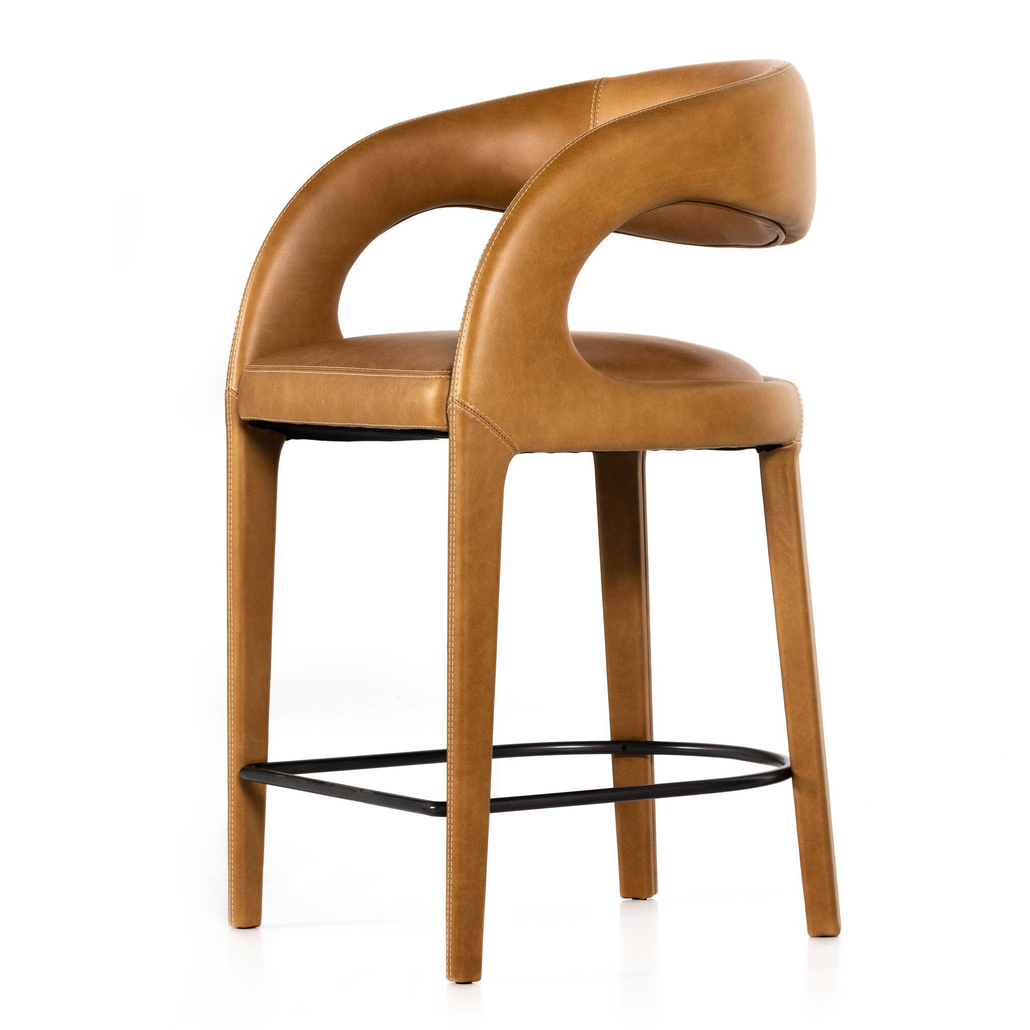 Counter stool 3/4 view with tan upholstery, curved arms, wood frame, and black footrest bar.