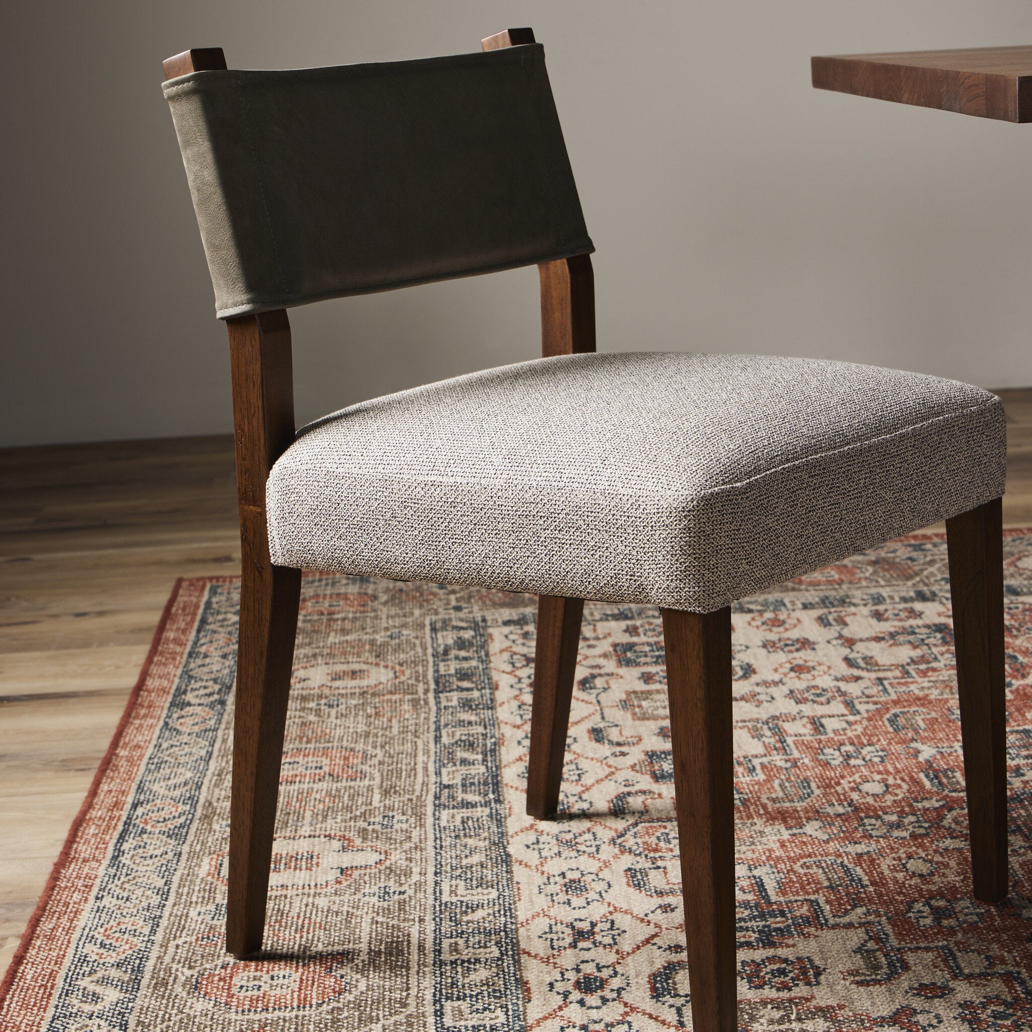 Armless dining chair with dark fabric backrest, beige upholstered seat, wood legs