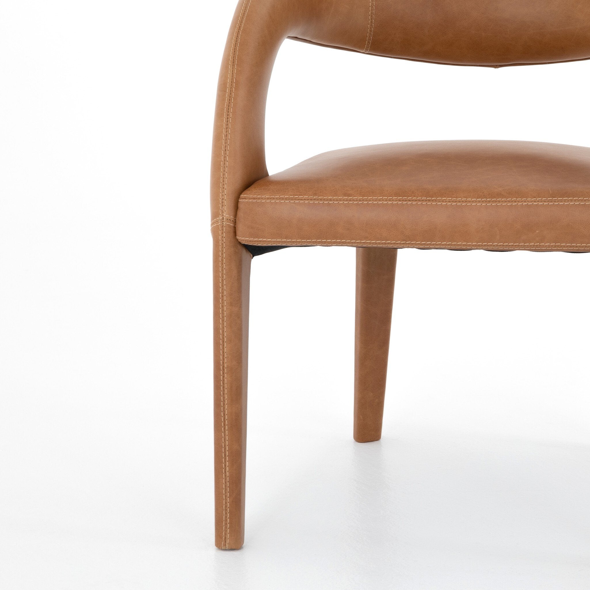 Brown leather chair on a white background. Hawkins Dining Chair in Sonoma Butterscotch top-grain leather with a sculpted open-back frame.