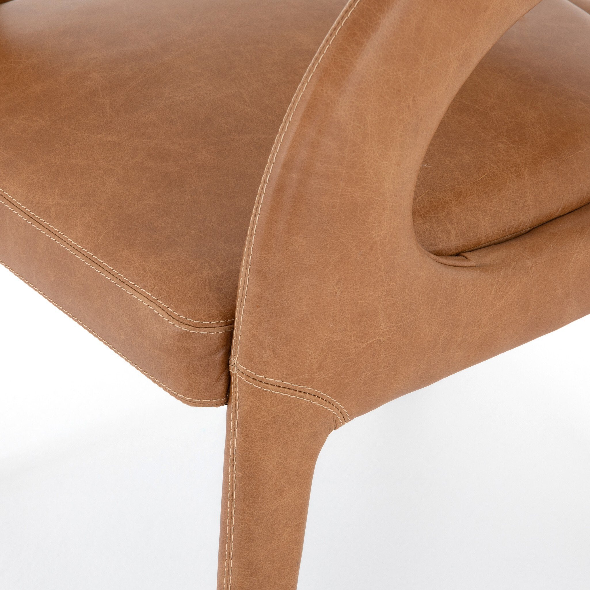 Close-up of a brown leather chair on a white background. Hawkins Dining Chair in Sonoma Butterscotch top-grain leather with a sculpted open-back frame.
