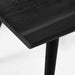 Close-up of a black wooden stool on a white background. Ripley Dining Chair in Black Oak with mid-century Windsor-style sculptural silhouette.