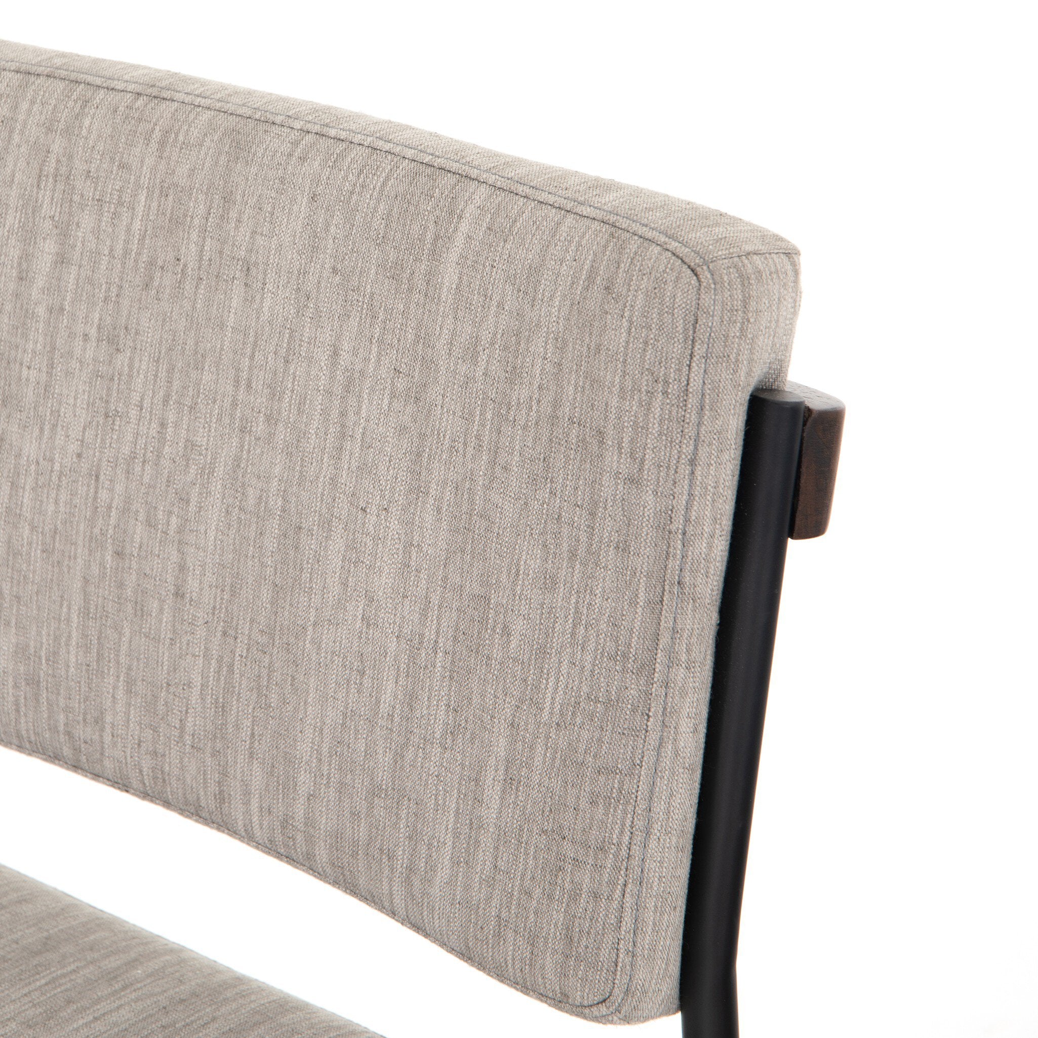 Close-up of a gray upholstered chair with a wooden armrest on a white background. Benton Dining Chair in Savile Flannel performance fabric featuring a slim iron frame and wood bar.