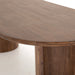 Close wooden detail Paden Dining Table in Seasoned Brown Acacia with crescent-shaped legs and an oval tabletop 