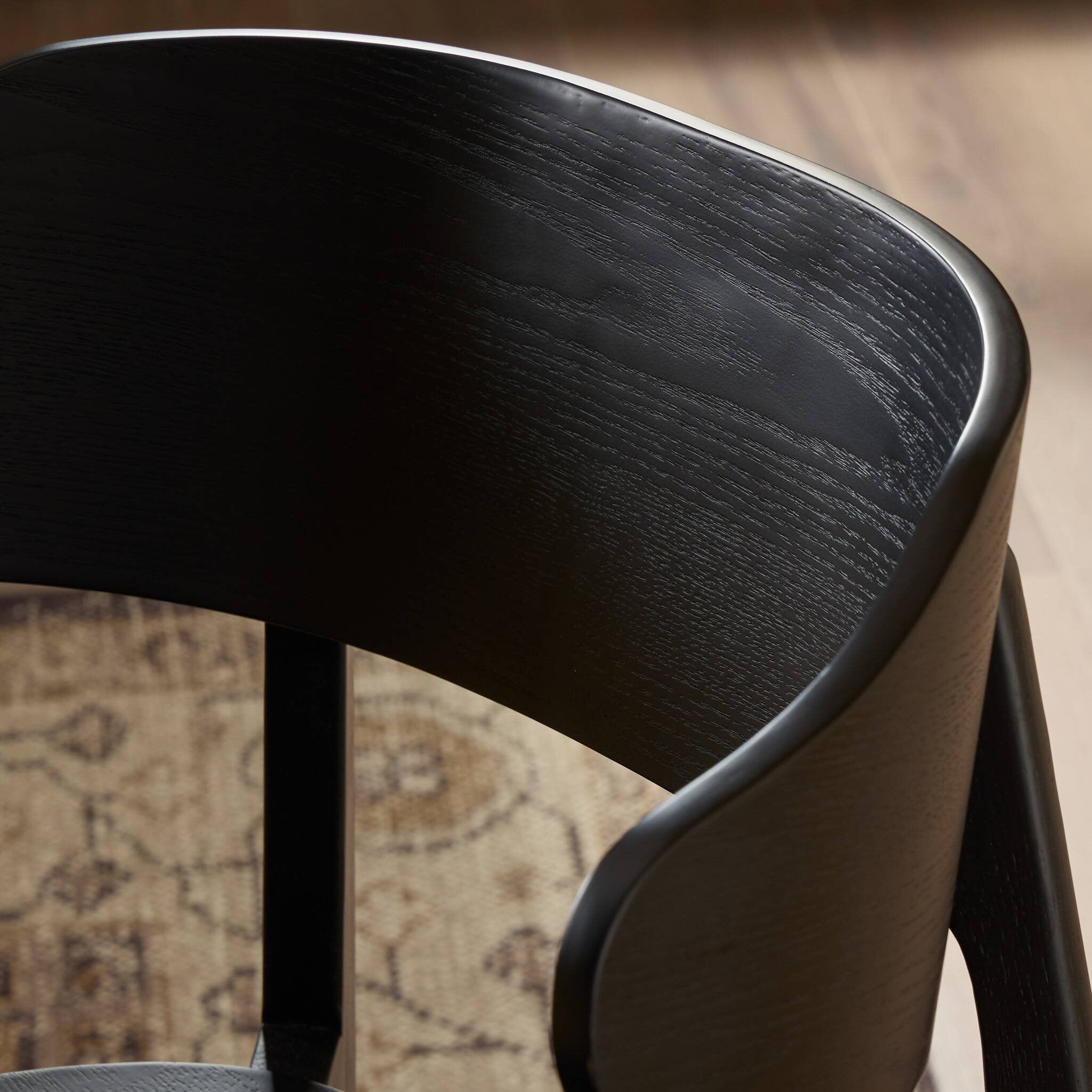 Black armless dining chair close-up of curved backrest and side panel