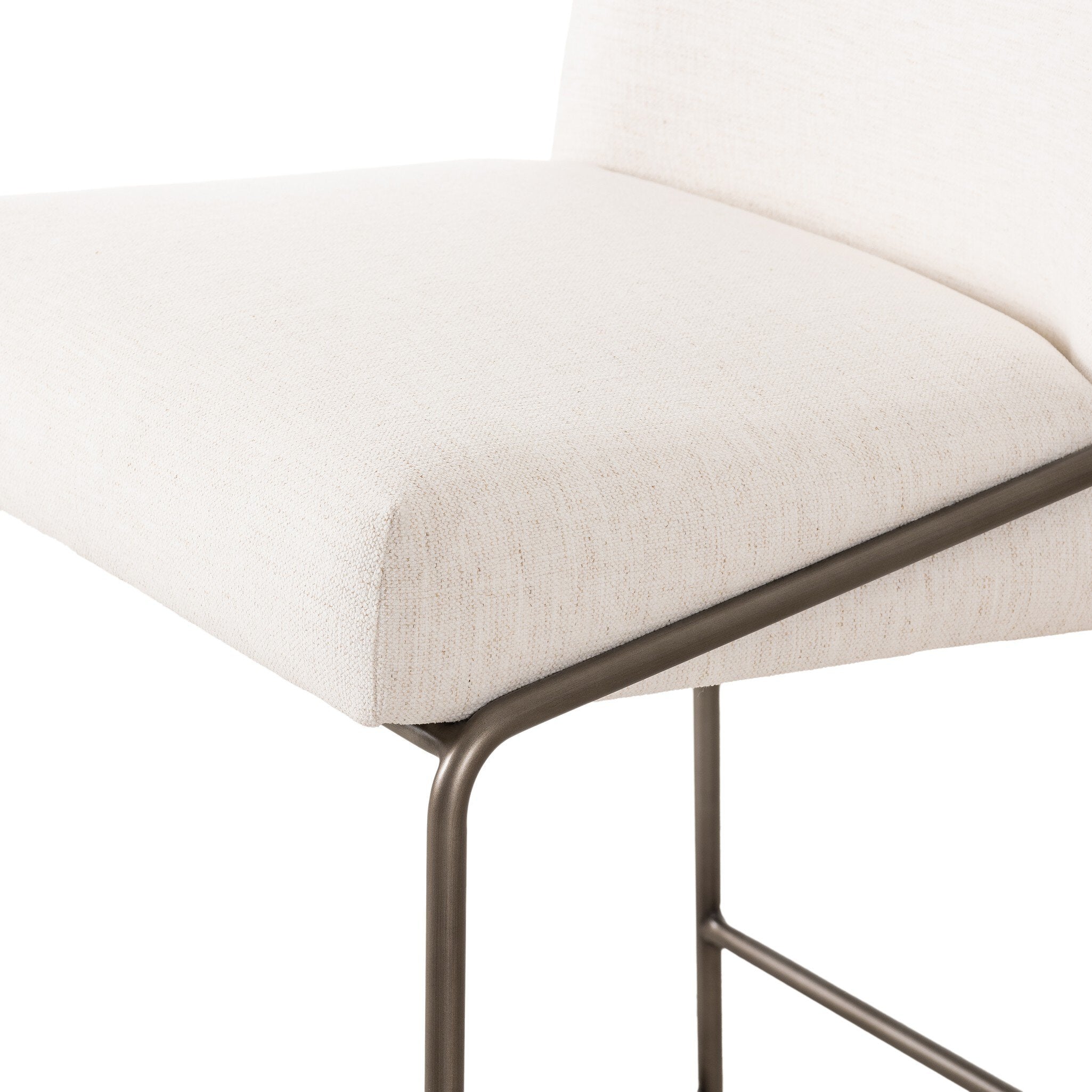 Close-up of light upholstered bar stool seat cushion edge with curved metal trim