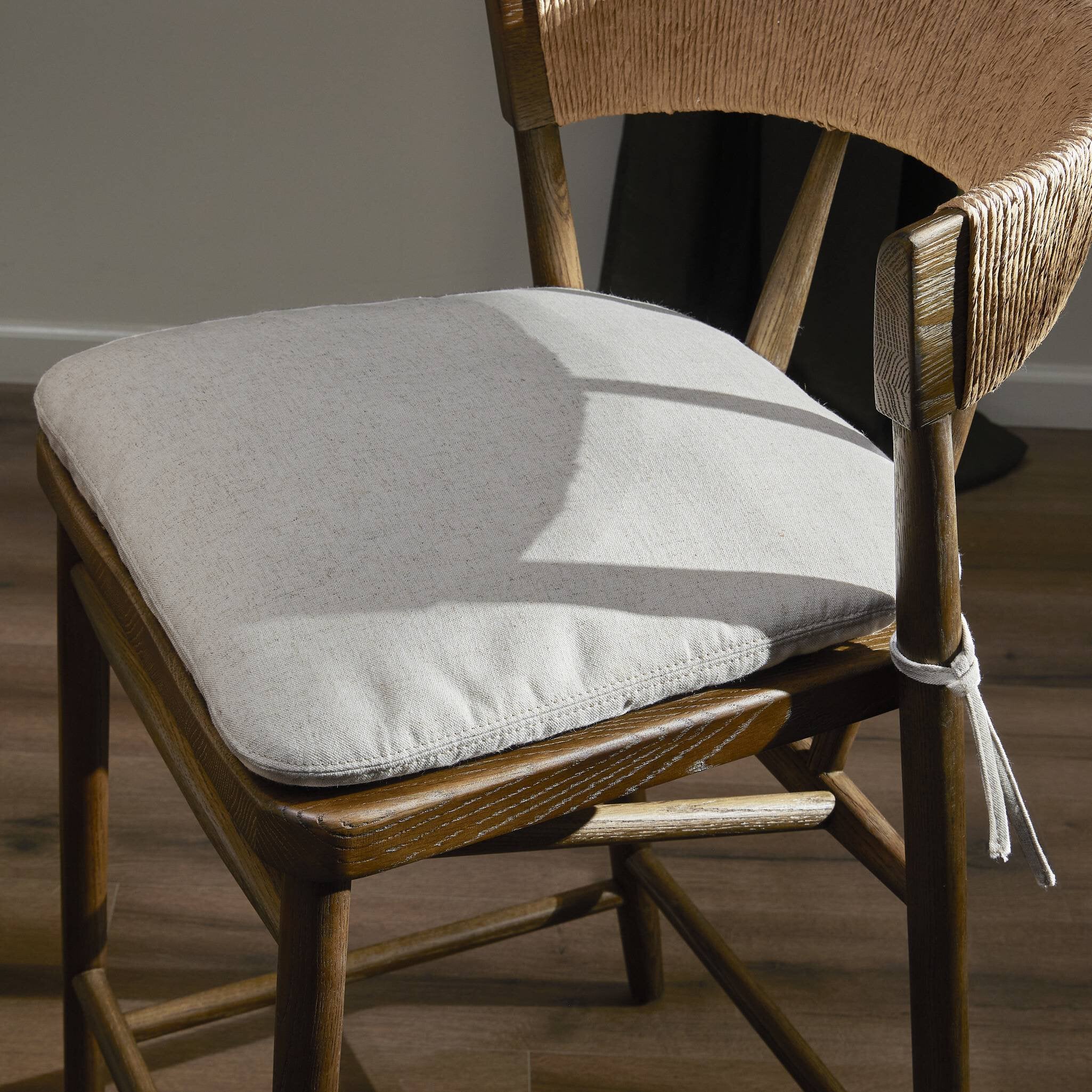 Cream padded bar stool seat with wooden frame and tied cushion