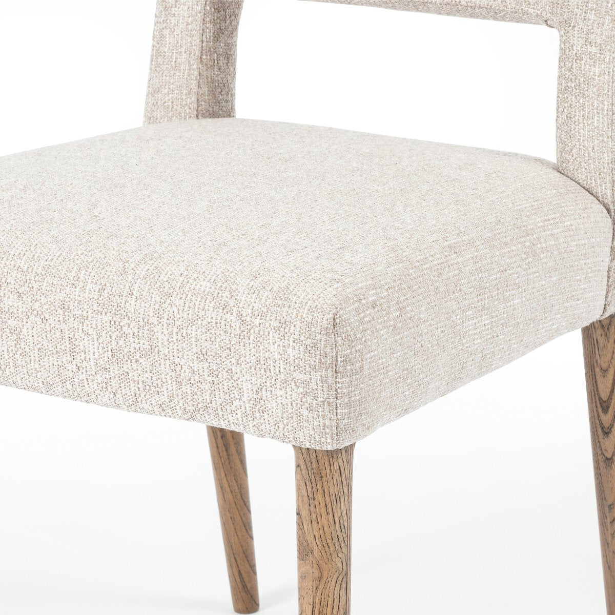 Armless dining chair armrest-free seat in light camel fabric, with tapered wooden legs.