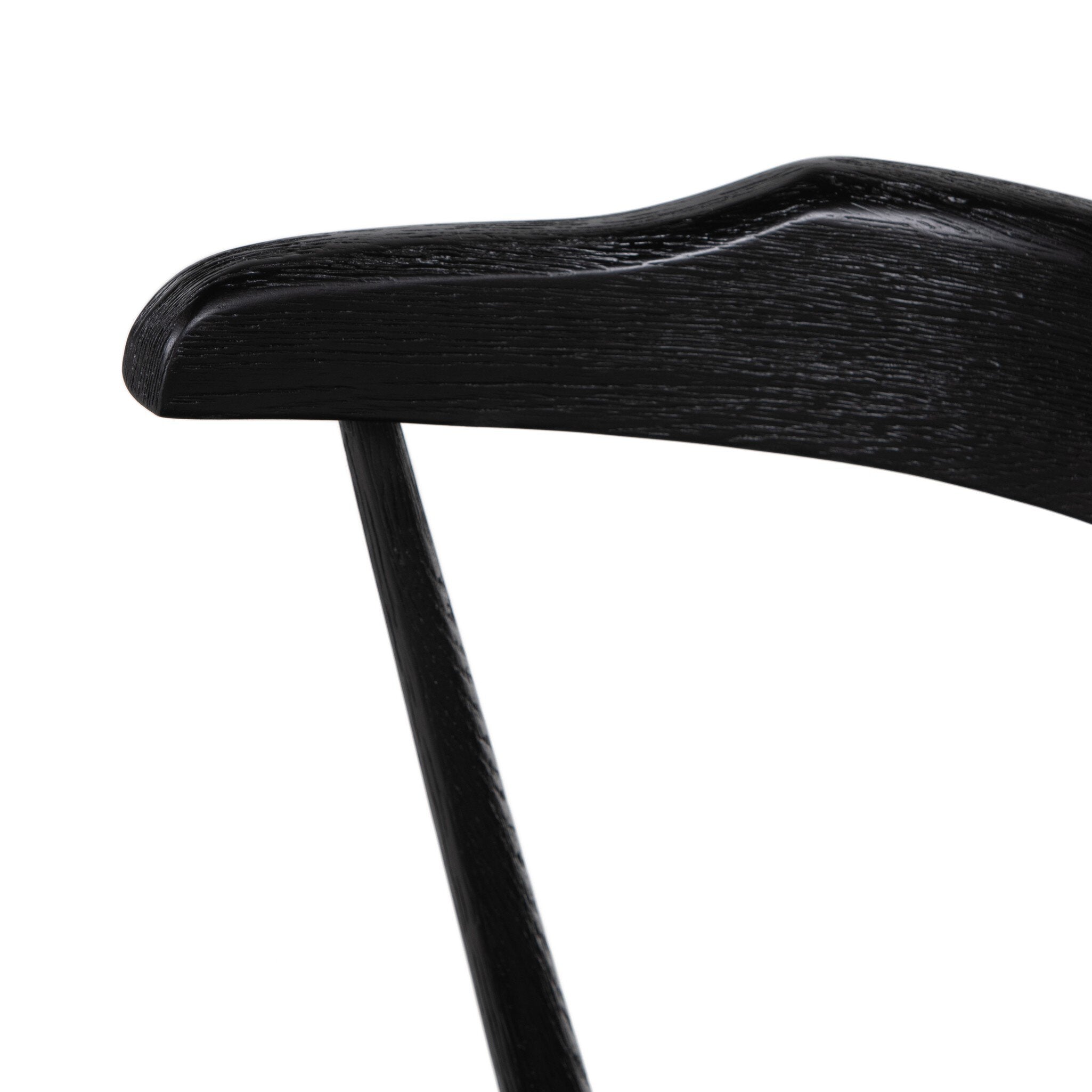 Close-up of a black chair armrest on a white background. Detail Ripley Dining Chair in Black Oak with mid-century Windsor-style sculptural silhouette.