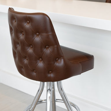 Detailed Fudge Brown Adler Bar Stool with a curved upholstered backrest and seat, featuring a sleek four-leg chrome frame and footrest