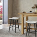 Natural linen counter stool with rounded seat, dark frame, and built-in footrest