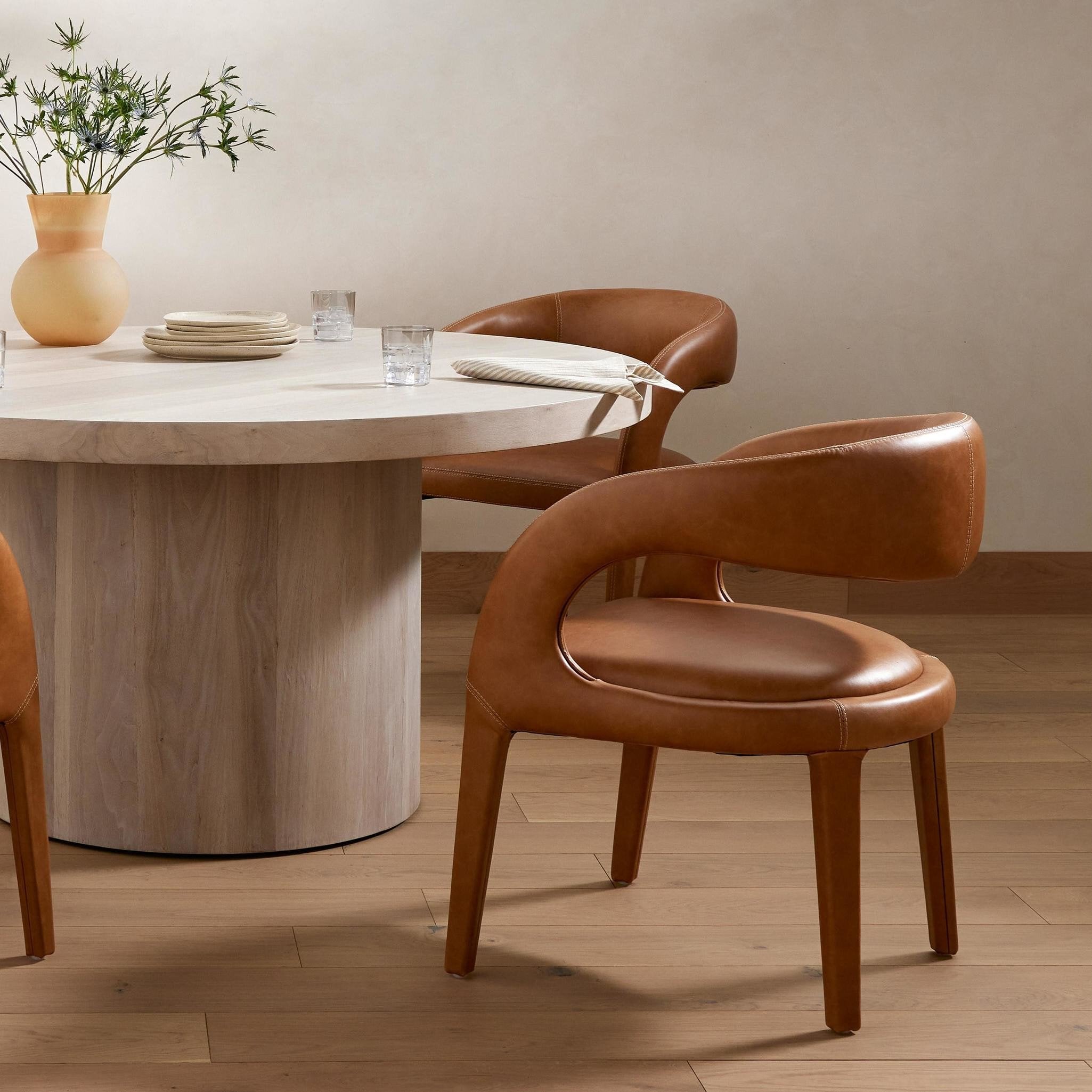 Dining table with chairs in a room setting. Hawkins Dining Chair in Sonoma Butterscotch top-grain leather with a sculpted open-back frame.