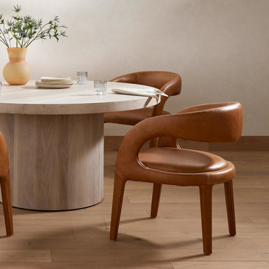 Dining table with chairs in a room setting. Hawkins Dining Chair in Sonoma Butterscotch top-grain leather with a sculpted open-back frame.