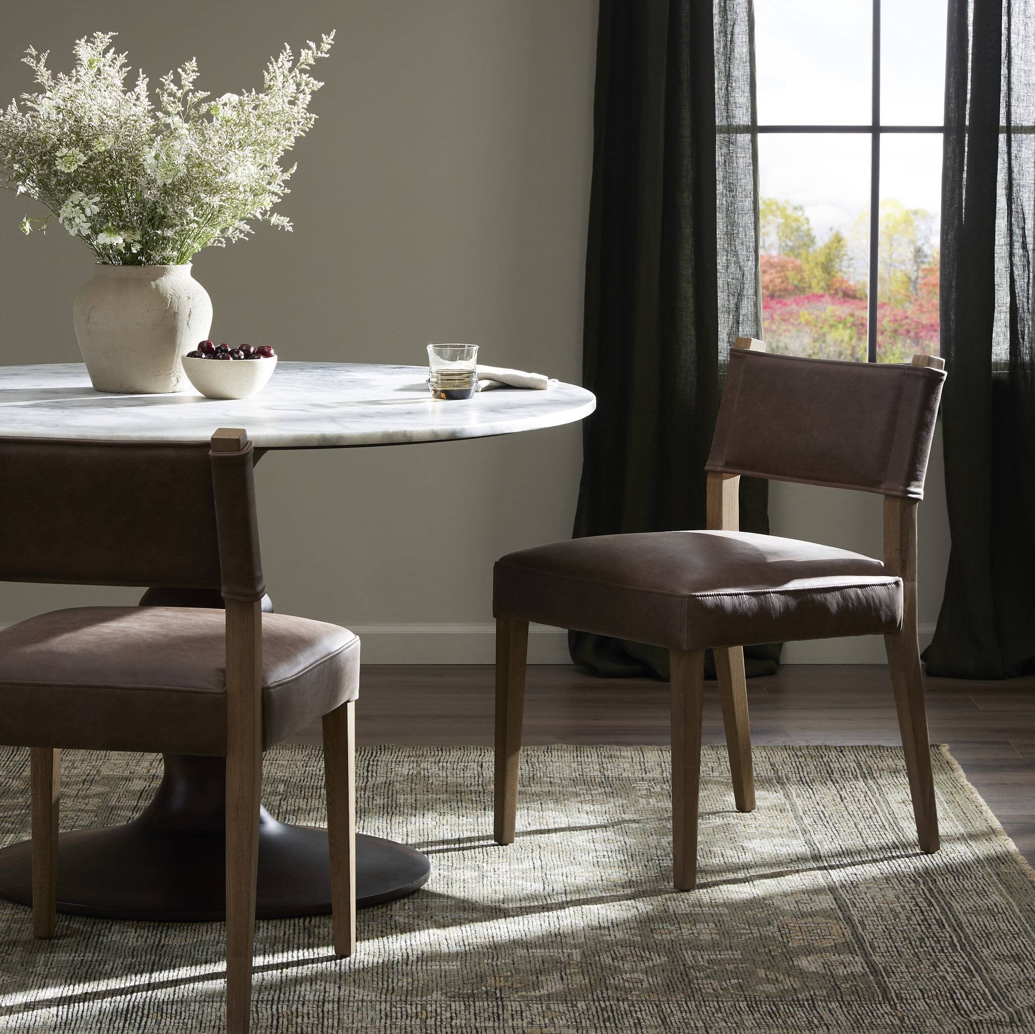 Brown armless dining chair in living room setting, upholstered seat and back, wood legs.