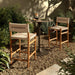 Outdoor bar counter stool in vintage white with woven back, armrests, and wood legs