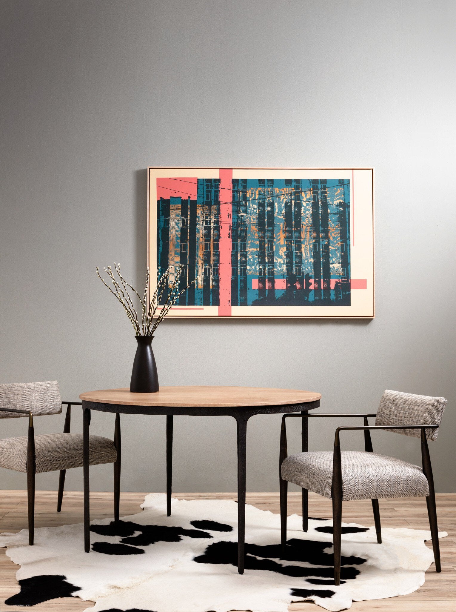 Dining room with round table and Waldon Dining Chair in Toasted Ash with textured ivory upholstery and an architectural wood frame, abstract art on the wall, and cowhide rug.