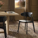 Black armless dining chair with curved backrest and round seat beside table