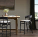 Bar stool with black frame, rounded upholstered back, and cream seat cushion