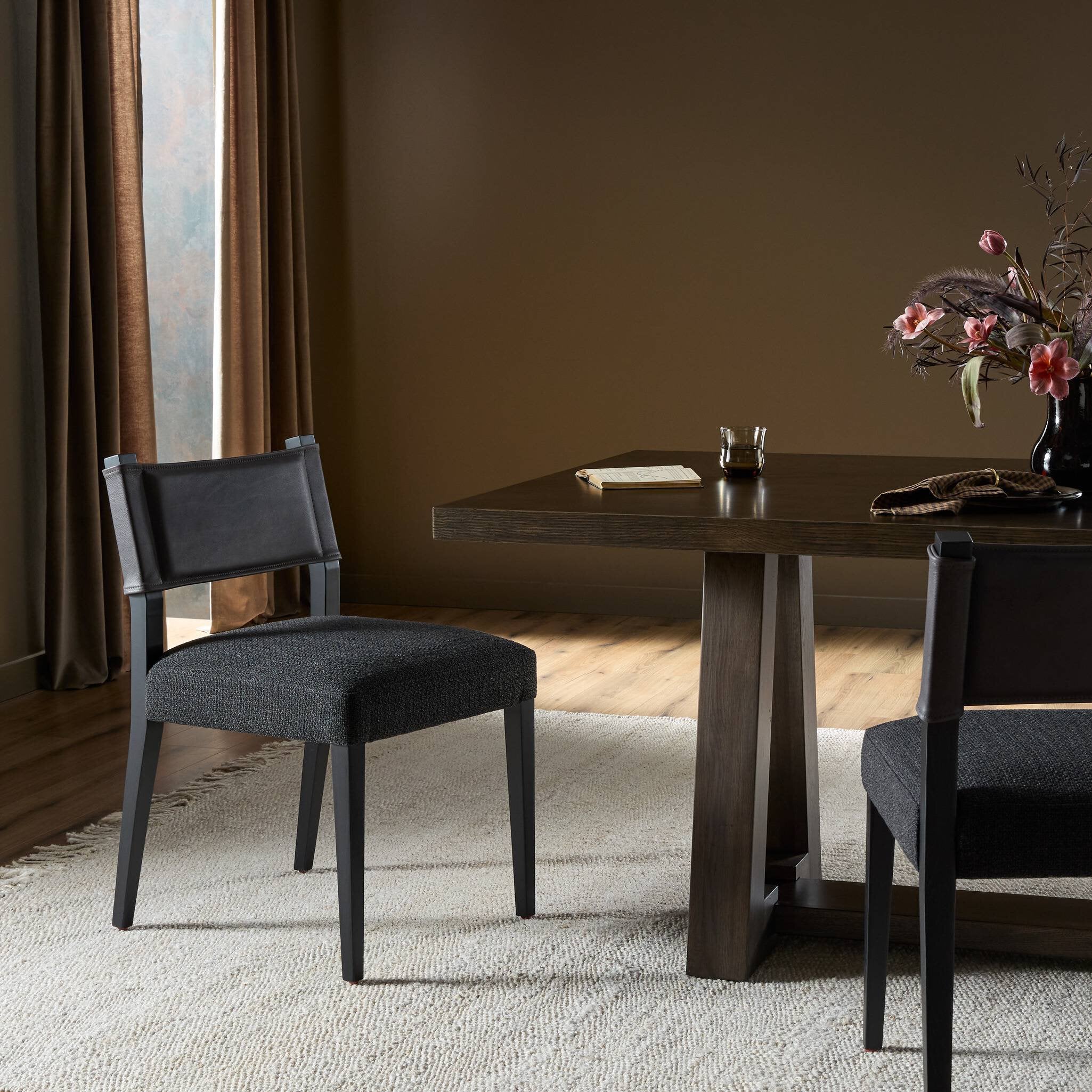 Armless dining chair with gray seat and dark upholstered back in a home dining setting
