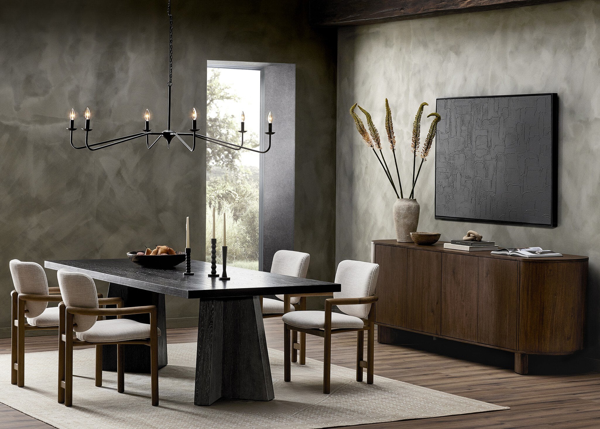 Modern dining room with a dark wooden table, four Madeira three-legged dining chair featuring a tubular frame and a curved barrel backrest in cream upholstery, and a chandelier.