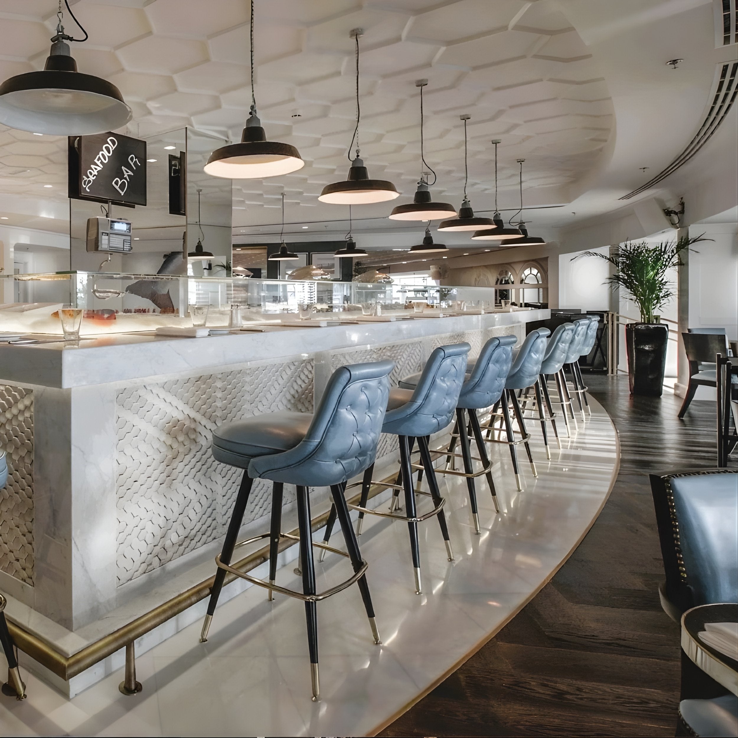 Modern bar interior with Tufted rolled edge modern bar stool featuring performance upholstery seat diamond buttons with black metal and silver stools and a decorative ceiling.
