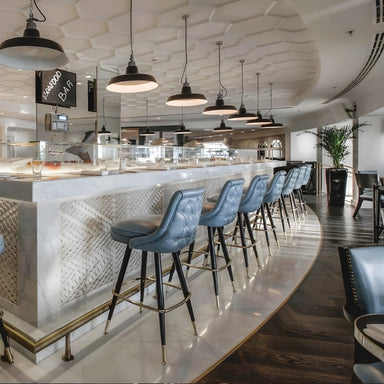 Modern bar interior with Tufted rolled edge modern bar stool featuring performance upholstery seat diamond buttons with black metal and silver stools and a decorative ceiling.